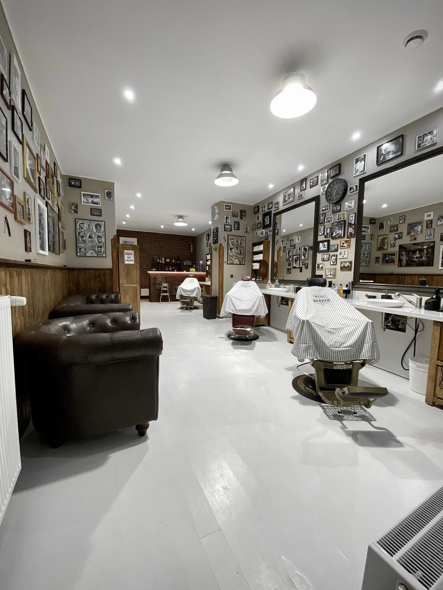 Tradiční interiér holičství Shelby Barber Shop se světlou podlahou a koženými křesly